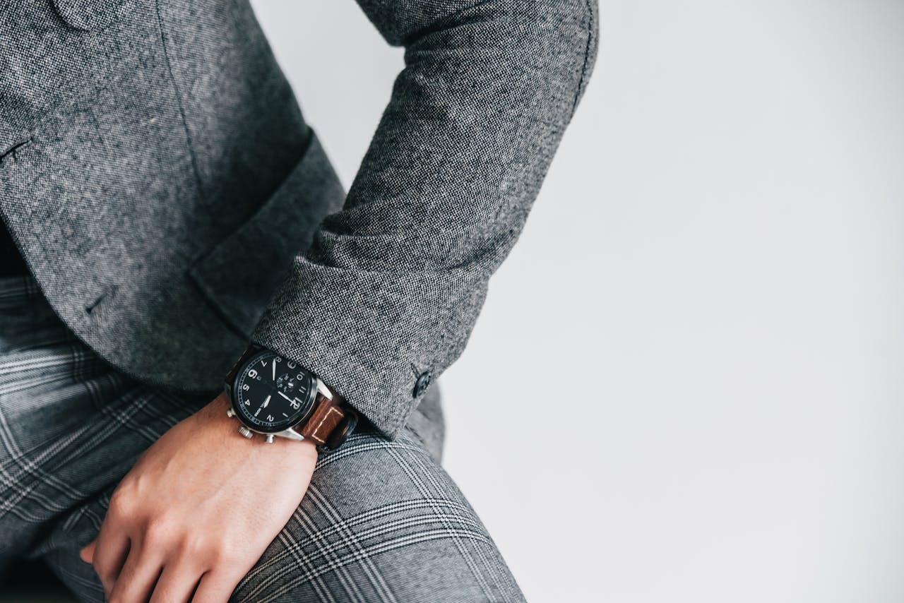 Close-up image of a person wearing a gray suit and checkered pants, showcasing a wristwatch.